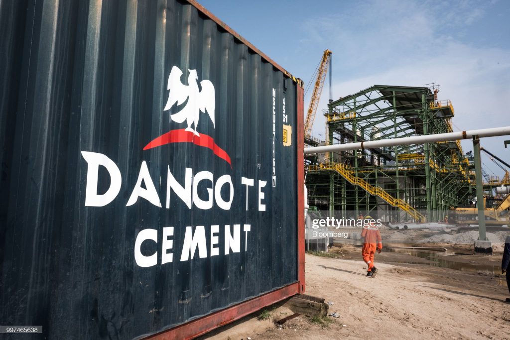 A Dangote Cement Plc logo stands on a barrier at the under-construction Dangote Industries Ltd. oil refinery and fertilizer plant site in the Ibeju Lekki district, outside of Lagos, Nigeria, on Thursday, July 5, 2018. The $10 billion refinery, set to be one of the worlds largest and process 650,000 barrels of crude a day, should be near full capacity by mid-2020, Devakumar Edwin, group executive director at Dangote Industries said in an interview. Photographer: Tom Saater/Bloomberg via Getty Images