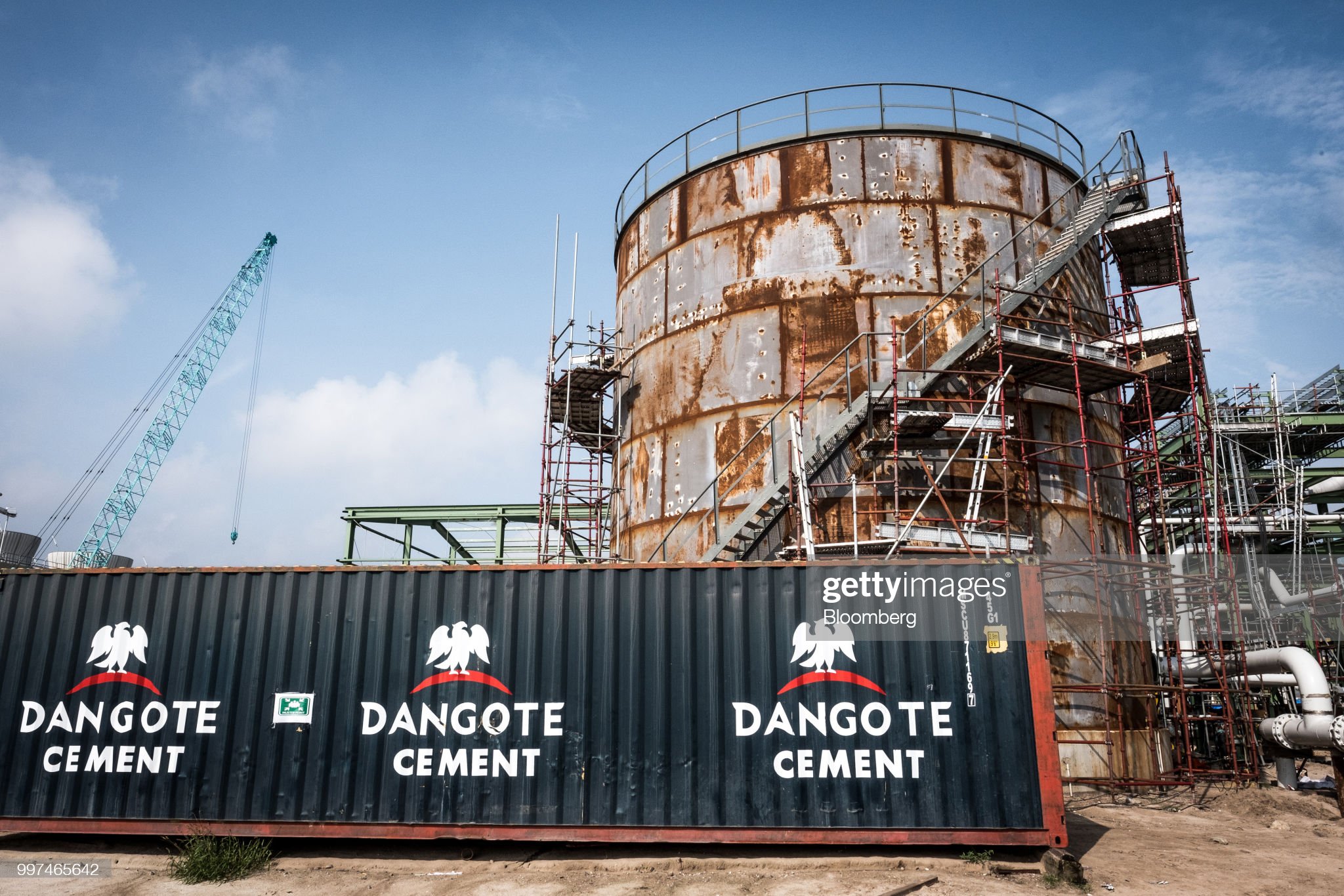 The Dangote Cement Plc logo stands on a barrier at the under-construction Dangote Industries Ltd. oil refinery and fertilizer plant site in the Ibeju Lekki district, outside of Lagos, Nigeria, on Thursday, July 5, 2018. The $10 billion refinery, set to be one of the worlds largest and process 650,000 barrels of crude a day, should be near full capacity by mid-2020, Devakumar Edwin, group executive director at Dangote Industries said in an interview. Photographer: Tom Saater/Bloomberg via Getty Images